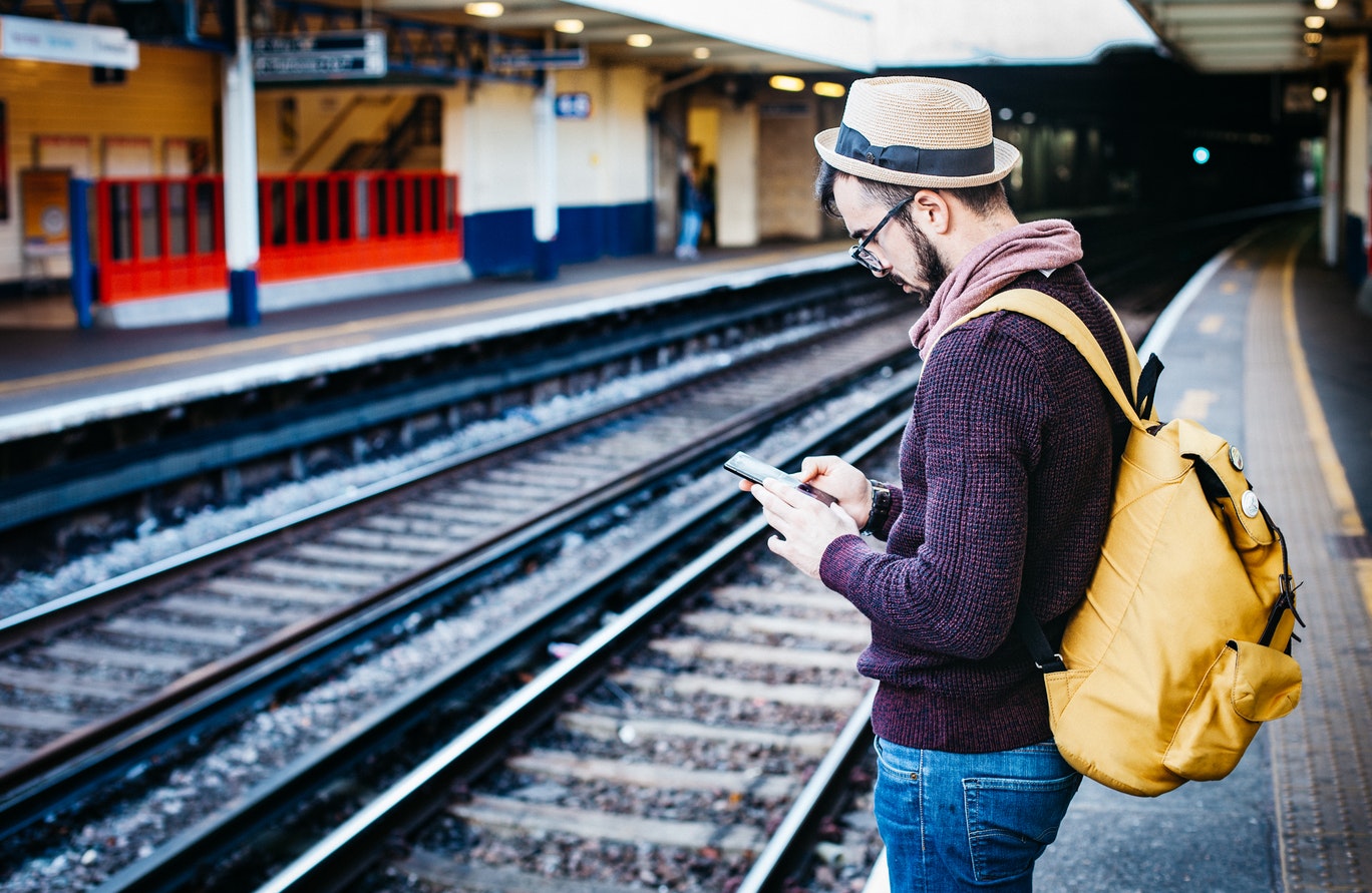 man using a mobile on station platform